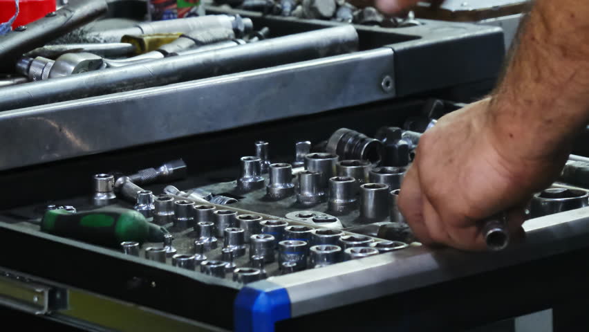 Mechanic hands chooses steel bits for car spanner in toolbox drawer at service station closeup. Employee works with manual tools in garage