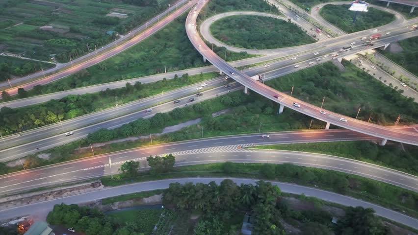 A drone shot of a complex highway interchange at dusk in Hanoi, Vietnam, with bright streetlights illuminating the curved ramps.