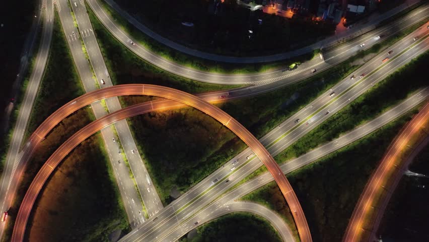 An abstract, top-down view of a highway interchange at night in Hanoi, Vietnam, with multiple illuminated overpasses and roadways.