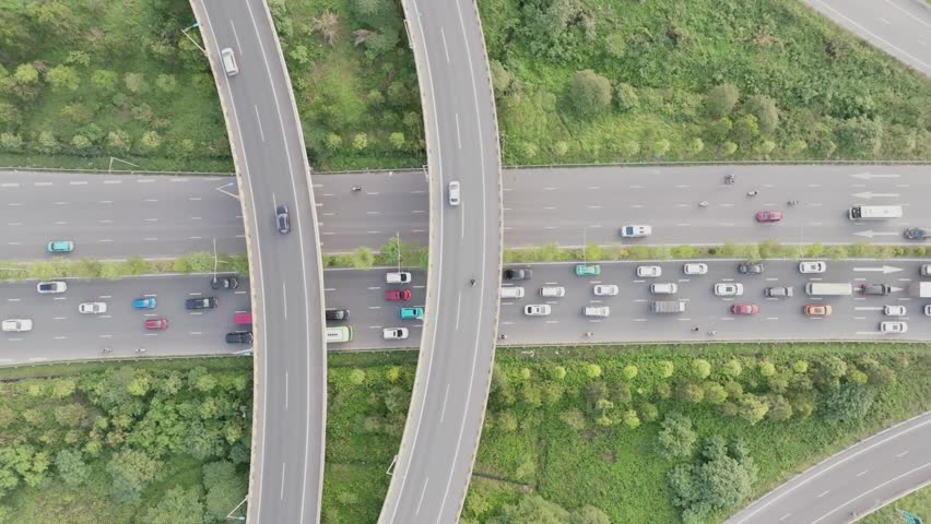 An overhead drone shot of a highway and a curving overpass in Hanoi, Vietnam, with heavy traffic on the main road.