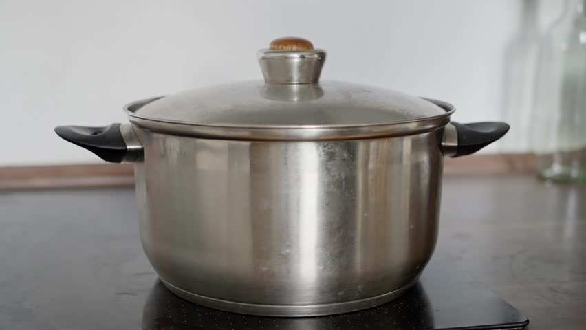 adult hands gently adjust cookware, closeup of hands managing stainless steel pots, adults skillfully handling stainless steel pots with precision on advanced induction cooking surface