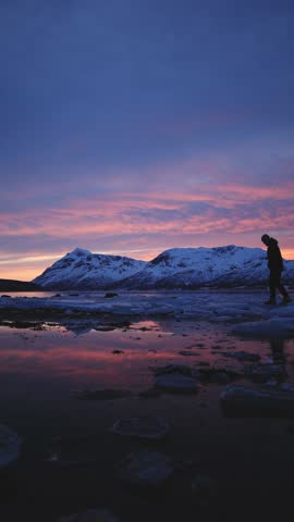 Man in winter clothing walks thoughtfully across ice crusts on the shore of the Atlantic Ocean during an icy winter in Northern Norway near Tromso. Curing depression