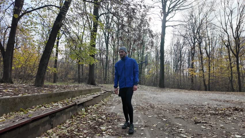 Man lying on a bench outdoors in autumn park doing abdominal crunch exercise in sportswear. Horizontal 4K footage.