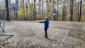Man stretching arms behind back on outdoor basketball court in autumn park, warming up before training. Horizontal 4K footage. - Powered by Shutterstock - Get 15% off with code: PIKWIZARD15