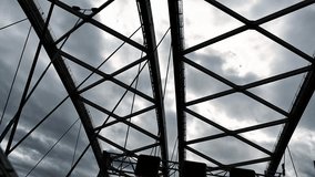 Low angle view of steel truss bridge with intersecting beams silhouetted against dramatic cloudy sky. Urban infrastructure, industrial architecture and geometric engineering design concept. - Powered by Shutterstock - Get 15% off with code: PIKWIZARD15