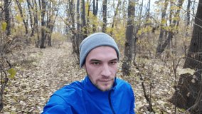Close-up portrait of man jogging in autumn forest, wearing blue jacket and gray beanie, focused on training. Vertical 4K footage. - Powered by Shutterstock - Get 15% off with code: PIKWIZARD15