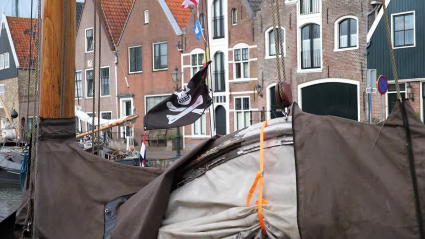Historic harbor with traditional wooden boats and pirate flag. Scenic European waterfront, old town architecture, maritime culture, and nautical atmosphere—perfect for travel and history lovers.