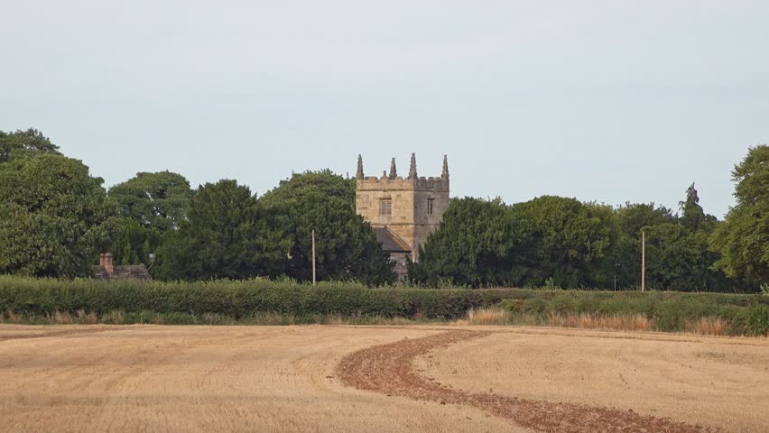 A rural farm with a church built in Norman architecture and trees