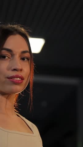 Portrait of beautiful sexy woman against dark wall background. Vertical video.