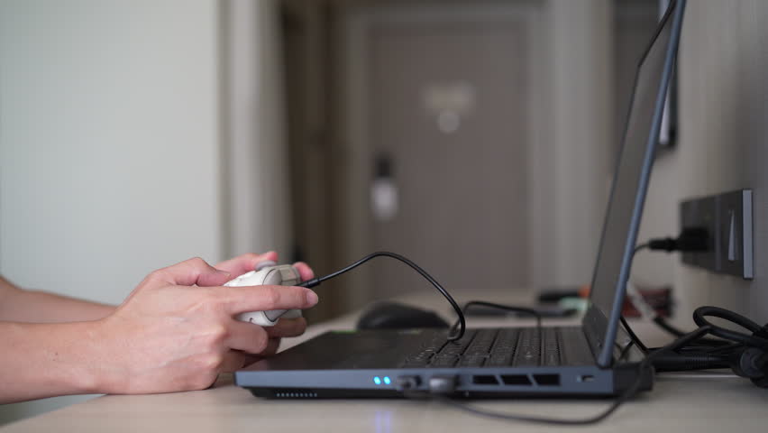 Closeup people hand or gamer holding wired joystick or gaming controller to enjoy playing game on computer notebook or laptop console by joy stick in living room for entertrainment relax on holiday