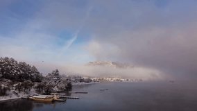 Beautiful winter landscape reveals snow-covered trees and serene lake waters. Fog drapes over nearby mountains, creating a mystical atmosphere. Soft light casts a magical glow at dawn. - Powered by Shutterstock - Get 15% off with code: PIKWIZARD15