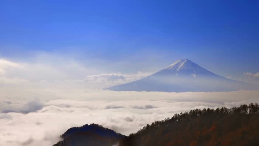 Glow of sunrise illuminates Mount Fuji rising above a sea of clouds. Lush green hills frame this iconic scene, showcasing natural beauty and serenity of Japan. Perfect for travel enthusiasts.