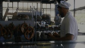 Baker analyzing user connections on mobile device while icons rippling across bakery display case. Artisan, retail, modern, digital, commercial, connectivity, network - Powered by Shutterstock - Get 15% off with code: PIKWIZARD15