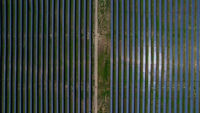 Aerial view of solar panels on sunny day in steppe mountainous area with forest, power farm producing clean energy.