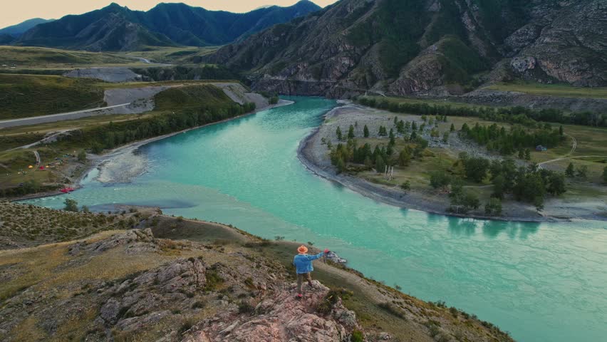 Aerial view tourist man hiker and Confluence of two rivers, division of color Katun and Chuya republic Altai mountains, Russia.