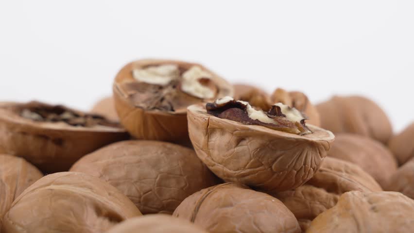 Cracked Walnuts. Rotating cracked walnuts reveal the nut inside their textured brown shells. The detailed close-up highlights freshness and natural nutrition.