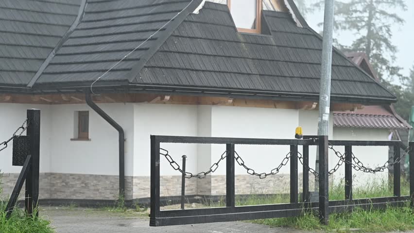 traditional house stands in rainy weather. Wet ground and dark clouds create moody village scene. Raindrops and wet surfaces around house emphasize stormy atmosphere and rural charm. - Powered by Shutterstock - Get 15% off with code: PIKWIZARD15