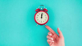 Creative flat lay concept top view of woman hand holding the red vintage alarm clock on bright blue turquoise color paper background with copy space in minimal style, template for text - Powered by Shutterstock - Get 15% off with code: PIKWIZARD15