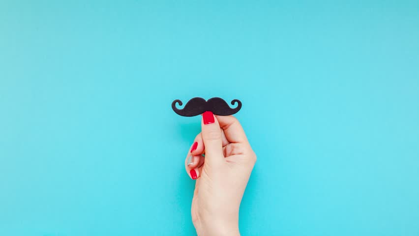 Creative flatlay top view retro black paper photo booth props moustaches woman hands turquoise background copy space. Men health awareness month fathers day masculinity concept blog social media