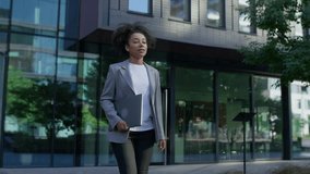 Young professional woman in a grey blazer confidently walking outside in a modern city environment while holding a closed laptop, symbolizing ambition and career drive. - Powered by Shutterstock - Get 15% off with code: PIKWIZARD15