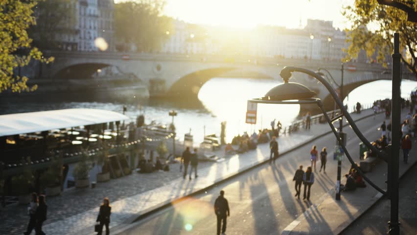 People walking along the seine river in paris at sunset