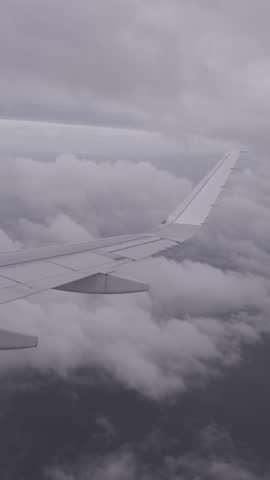view of airplane wing in the sky with clouds in vertical