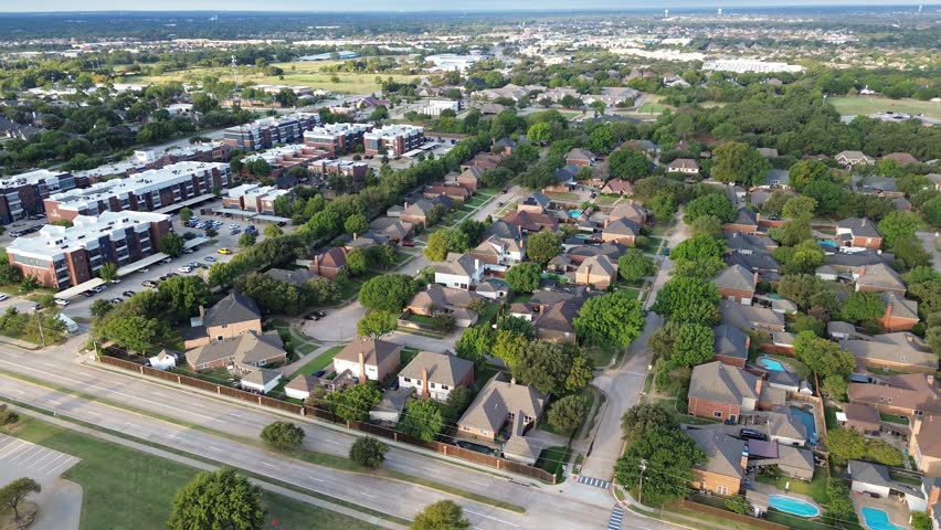 Highland Village, Texas mixed-use zone upscale homes with backyard pools, multistory modern apartment buildings with pond, flat roofs, covered surface parking, tree-lined streets, FM 407 corridor. USA