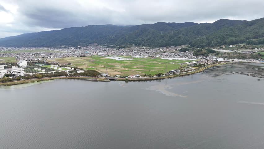 A city with a lake in the background. The lake is calm and the city is surrounded by mountains