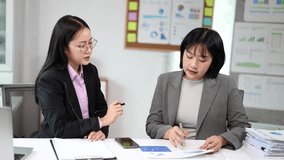Professional asian businesswomen working together in an office, pointing at documents with graphs and charts while discussing data analysis, strategy, and company growth during a productive meeting - Powered by Shutterstock - Get 15% off with code: PIKWIZARD15