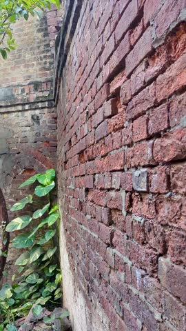 Ruins of old abandoned red brick house with broken door and green grass inside. Damaged and Apocalyptic building concept