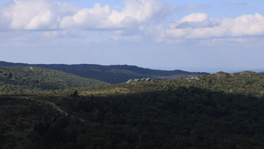 Peaceful summer landscape overlooking Massie Gap from Big Pinnacle Overlook in Grayson Highlands State Park, Virginia. Rolling forested hills and clouds create a serene mountain view.