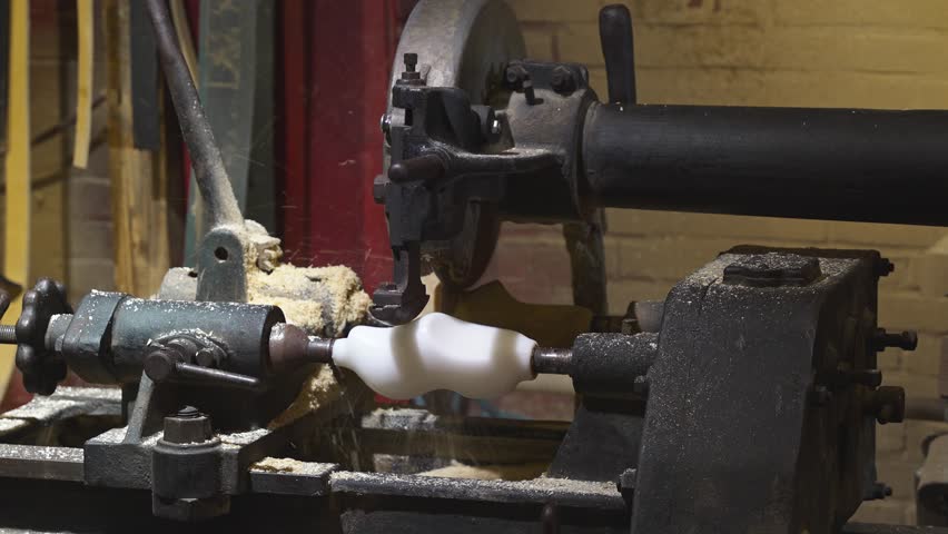 Close-up of a spinning clog shoemaking lathe shaping white mold, with visible sawdust and retro workshop background, shoemaking machinery, traditional Dutch shoe