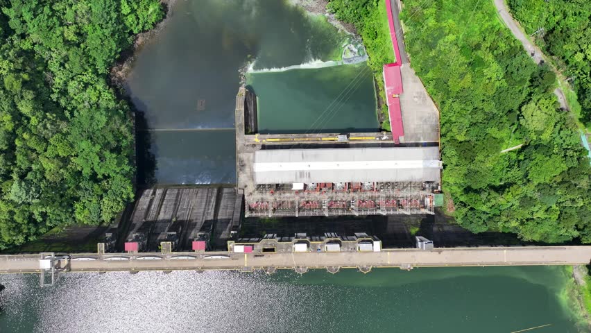 4k aerial video footage of Bayano Dam with Hydroelectric Power Plant, located at Bayano Lake - flying backwards and panning from top view to forward view - Panama rainforest landscape in background
