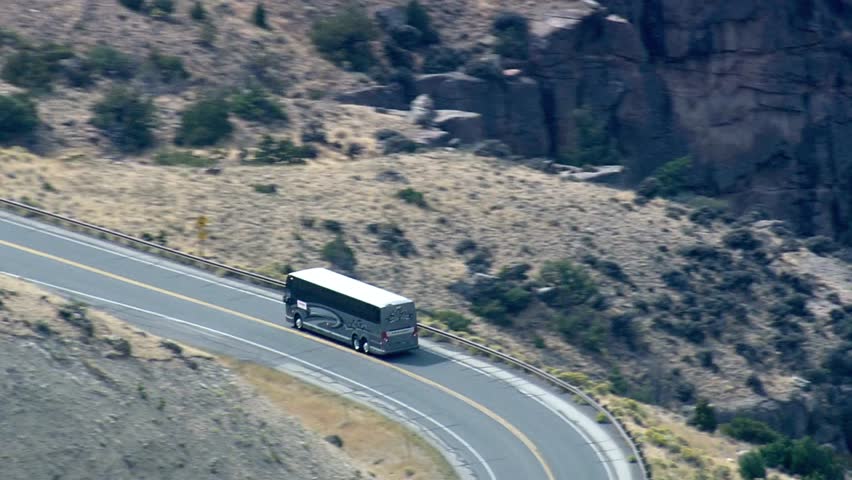 Scenic view of a winding road through a canyon with a bus driving along the path