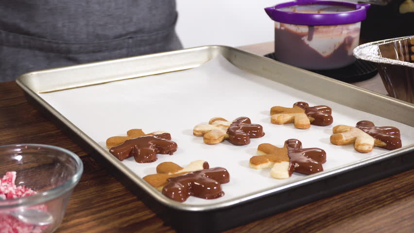 Preparing star-shaped cookies, half-dipped in chocolate, accented with peppermint chocolate chips for the holidays.
