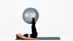 Young woman practicing pilates with a stability ball in a bright studio - Powered by Shutterstock - Get 15% off with code: PIKWIZARD15