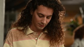 Close up of a young male student with long curly hair focused on using a digital tablet, possibly for studying or browsing online - Powered by Shutterstock - Get 15% off with code: PIKWIZARD15