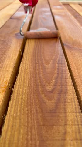 Manually applying a protective solution to wood using a roller. Close-up of the roller rolling over the wood.
