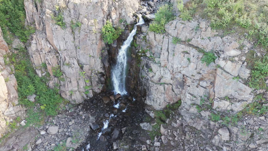 Warm afternoon light illuminates a vertical waterfall in a tall basalt cliff not far from Lake Lama in the Putorana Plateau. Fresh water, moss and stone create a powerful wilderness landmark for trave