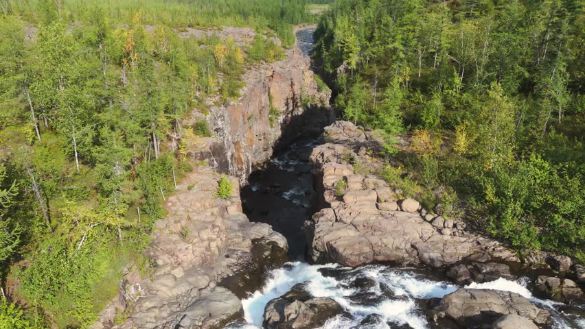Aerial view of a basalt canyon with a cold river carving the plateau. Larch forest, lava wall and foaming rapid reveal harsh beauty of the Putorana Plateau wilderness in far north Siberia, Russia
