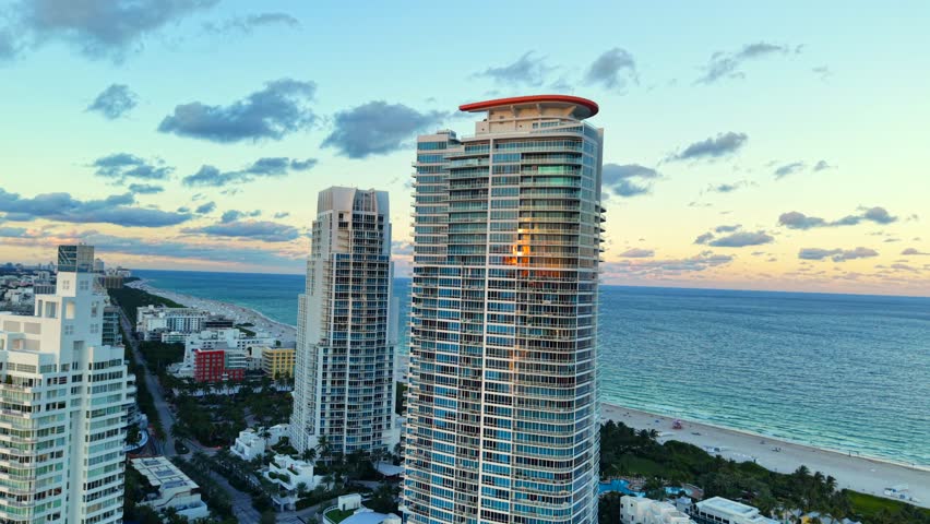 Drone roll inverted flight Miami Beach scene at sunset. Aerial view of Miami Beach Ocean Drive and highrise condominium towers on the sea