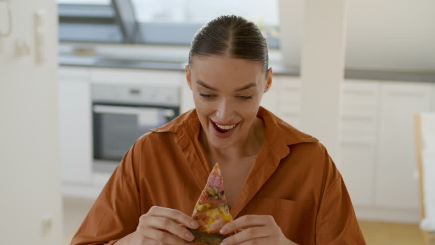 Woman Enjoying a Slice of Pizza at Home While Feeling Relaxed and Comfortable