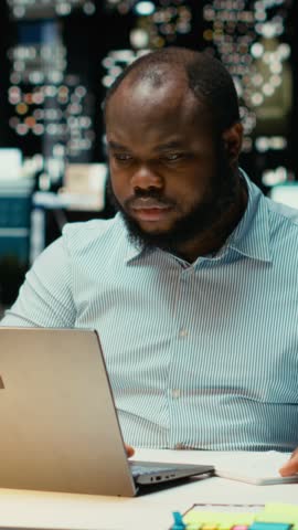 Vertical Video African american strategist ripping a paper after writing the wrong idea, restarting work in rage and crumpling the page sheet. Discontent man does a typo mistake while transcribing