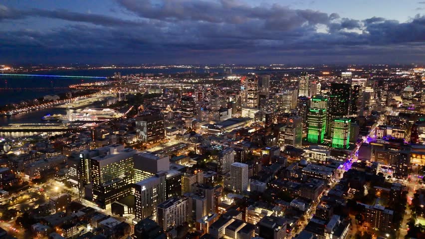 Montreal skyline at dusk with glowing city lights and dramatic clouds over horizon. g.