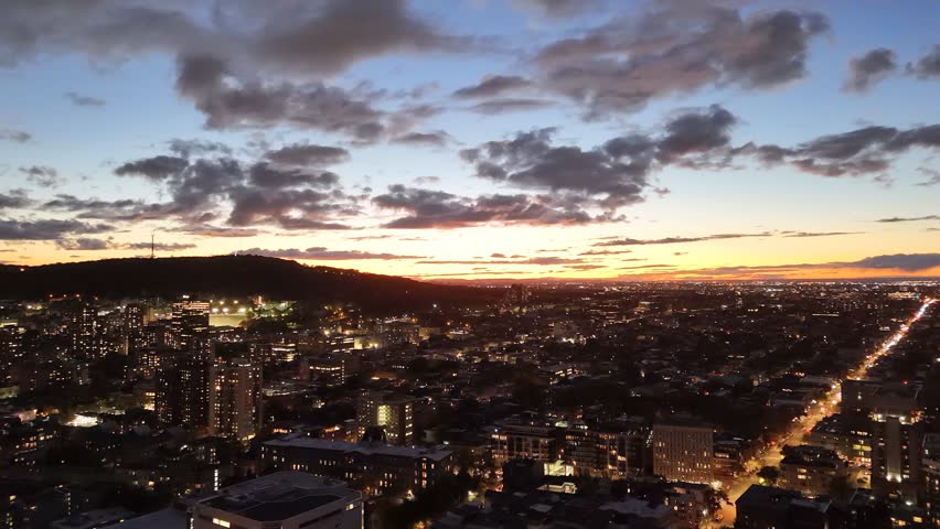 Montreal skyline at dusk with glowing city lights and dramatic clouds over horizon. g.