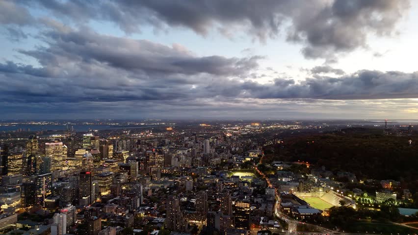 Montreal skyline at dusk with glowing city lights and dramatic clouds over horizon. g.