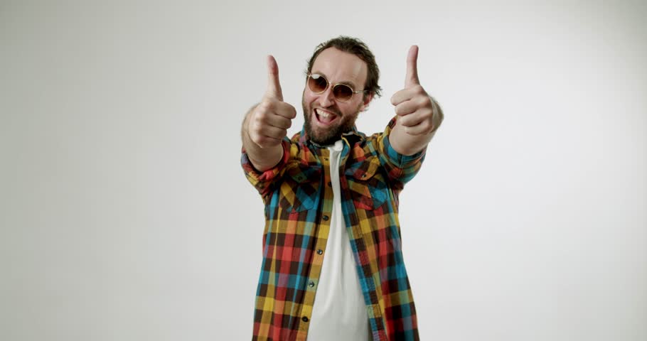 Excited man giving two thumbs up with cheerful smile. Happy guy in sunglasses showing like gesture. Positive emotions, approval, agreement, like, satisfaction, and recommendation concept.