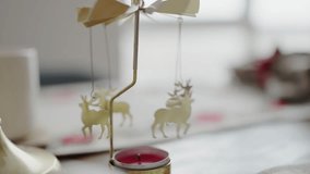 Close-up of a Christmas-themed table decoration featuring a delicately designed reindeer candle carousel, creating a serene and festive atmosphere. Christmas Table Decor with Reindeer Candle Carousel - Powered by Shutterstock - Get 15% off with code: PIKWIZARD15