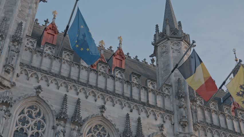 A majestic, low-angle view of the highly decorative Gothic Revival façade of the Provinciaal Hof (Provincial Court) on the Burg Square in Bruges, Belgium.