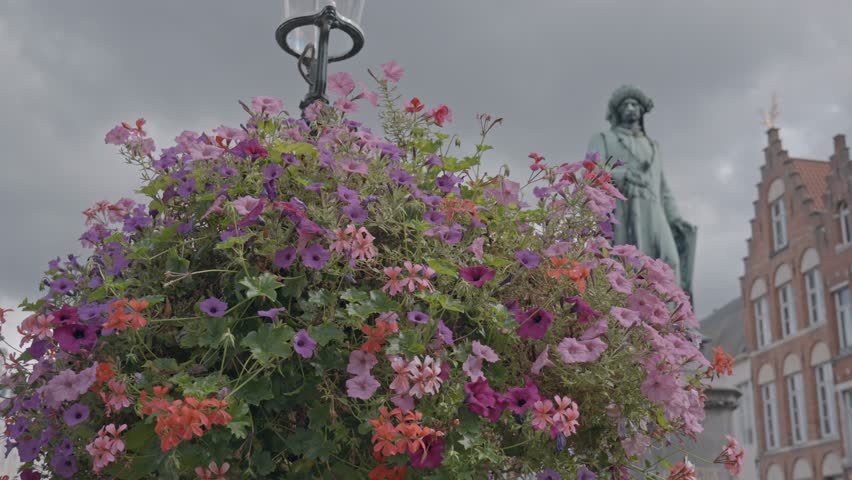A low-angle view of the Statue of Jan van Eyck in Jan van Eyckplein (Jan van Eyck Square), a historic square in Bruges, Belgium.